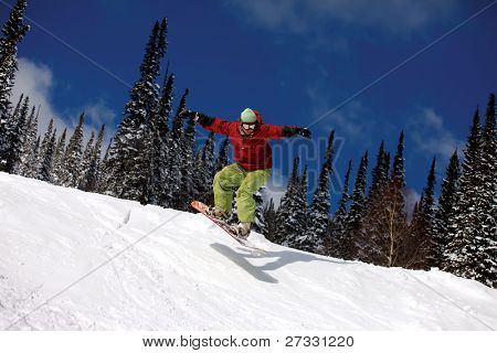 Snowboardista skoky vzduchem s tmavě modrou oblohou v pozadí