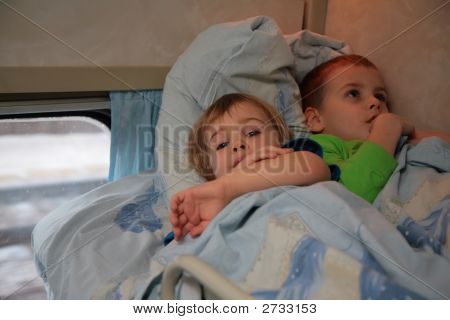Duas crianças encontram-se na cama no trem