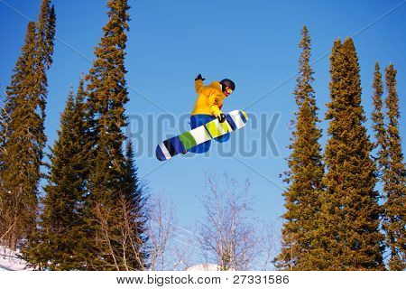 Snowboardista skoky vzduchem s tmavě modrou oblohou v pozadí