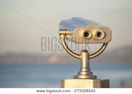 Public Binocular On Sea Shore, Close Up. Coin Operated Binocular Viewer On Blurred Background Of Sun