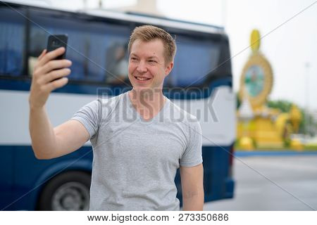 Young Happy Tourist Man Taking Selfie Against Ratchadamnoen Street In Bangkok