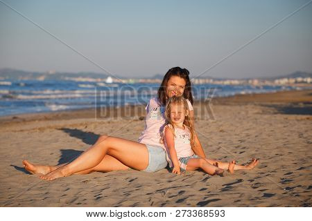 Woman And Kid In The Same T-shirs Posing On Beach. Smiling Mother With Daughter In Rimini. Famaly Va