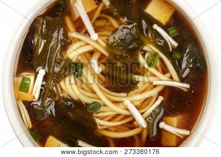 A Closeup Of A Bowl Of Miso Soup With Tofu, Scallions, Noodles, Wakame, And Enoki Mushrooms, Shot Fr