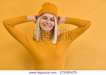 Portrait Of Pretty And Charming Young Woman With Blonde Hair Wearing Yellow Clothes, Smiling And Nar