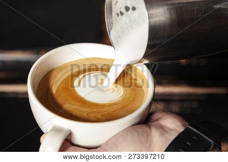 A Professional Barista Holds A Cup Of Coffee, Making A Beautiful Heart Shape Latte Art. Hot Art Latt