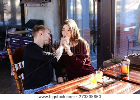 Couple Sitting Near Table With Sea-buckthorn Broth In Cafe Discu