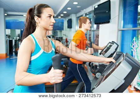 Cardio training. Woman and man at cross-trainers in gym