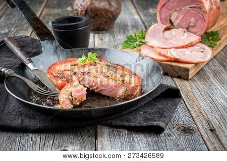 Traditional Allgauer veal roast roll sausage slices fried in a wrought-iron pan with spices as closeup