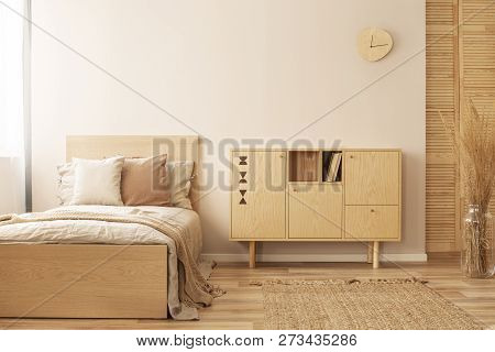 Single Wooden Bed With Beige Bedding And Blanket Next To Stylish Wooden Cabinet In Elegant Bedroom