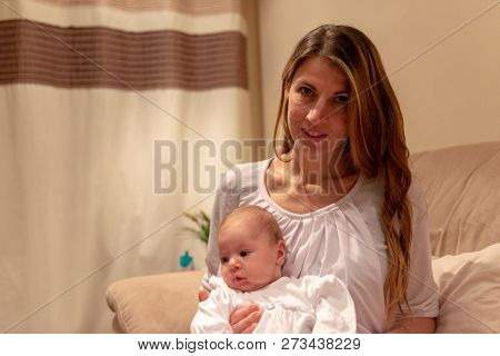 Caucasian Female Sitting On The Armchair Holding 2 Weeks Old Newborn Baby In The Living Room