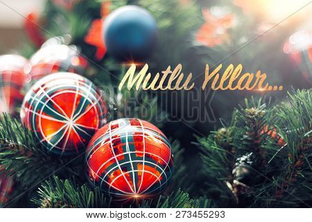 Closeup Of Shiny Red Bauble Hanging From A Decorated Christmas Tree. Mutlu Yillar Means Happy New Ye