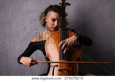 Young Woman With Acne Playing The Cello. Pits And Potholes On The Skin Of The Face.