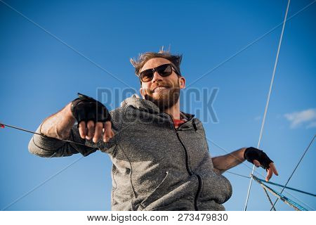 Man Wearing Sunglesses Sitting In A Sailing Vessel Feeling Happy In The Open Sea And Blue Sky Above