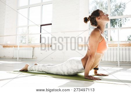 Taned Fit Woman Practicing Yoga Indoor White Class. Athletich Strong Girl Practice Cobra Asana In Su