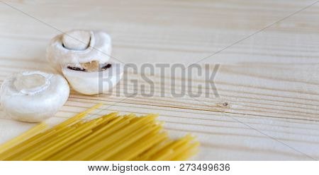 Wooden Background With Spaghetti And Mushrooms. Food Background Italian. Raw Champignons And Pasta O