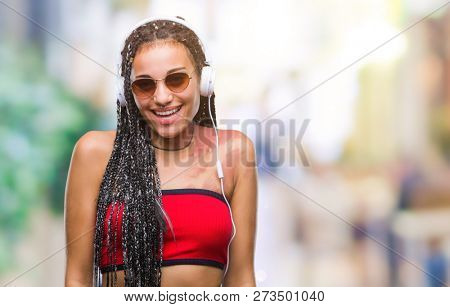Young braided hair african american with birth mark wearing headphones over isolated background with a happy and cool smile on face. Lucky person.