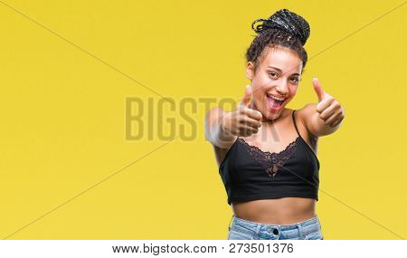 Young braided hair african american with pigmentation blemish birth mark over isolated background approving doing positive gesture with hand, thumbs up smiling and happy for success. Looking