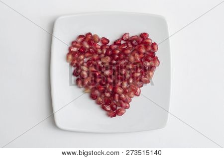 Red Pomegranate Seeds In Shape Of Heart In A Dish