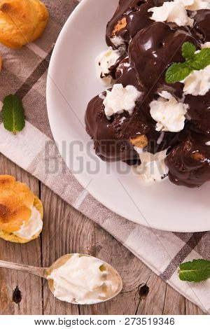 Chocolate Profiteroles With Whipped Cream On White Dish.