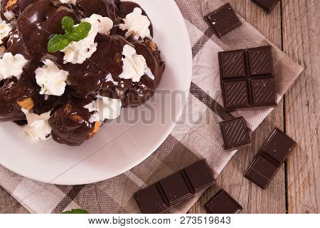 Chocolate Profiteroles With Whipped Cream On White Dish.