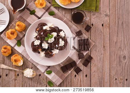 Chocolate Profiteroles With Whipped Cream On White Dish.