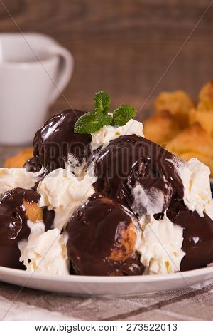 Chocolate Profiteroles With Whipped Cream On White Dish.