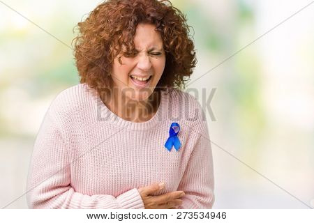 Middle ager senior woman wearing changeable blue color ribbon awareness over isolated background Smiling and laughing hard out loud because funny crazy joke. Happy expression.