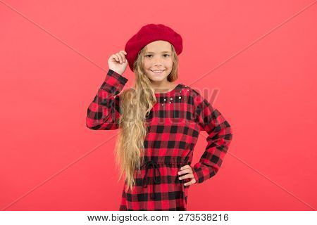 Kid Little Cute Girl With Long Blonde Hair Posing In Beret Hat And Checkered Dress Red Background. F