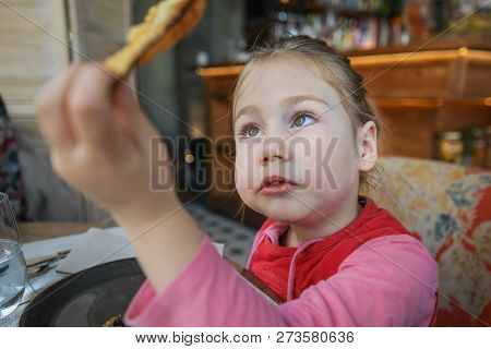 Little Girl Looking At Fried Eggplant Slice In Restaurant