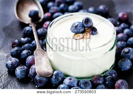 Serving Of Yogurt With Whole Fresh Blueberries And Oatmeal On Old Rustic Table