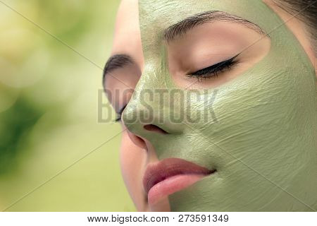 Macro Close Up Head Shot Of Attractive Woman With Green Algae Facial Mask In Spa.