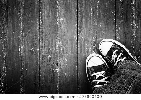 Clothes, Shoes And Accessories - Top View Closeup Legs Put In Gumshoes And Jeans Top View On A Woode
