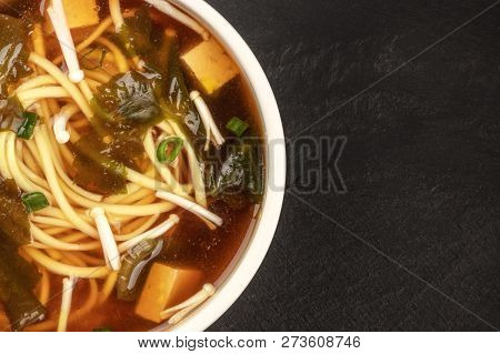 A Closeup Of A Bowl Of Miso Soup With Tofu, Scallions, Noodles, Wakame, And Enoki Mushrooms, Shot Fr
