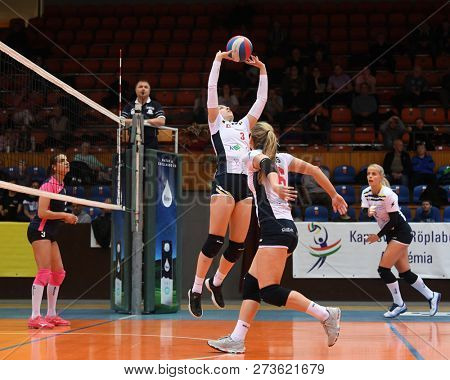 KAPOSVAR, HUNGARY â DECEMBER 2, 2018: Viktoria Kalmar posts ball at a Hungarian National Championship volleyball game between Kaposvar (white) and Palota VSN (blue) in Sportcsarnok Kaposvar.