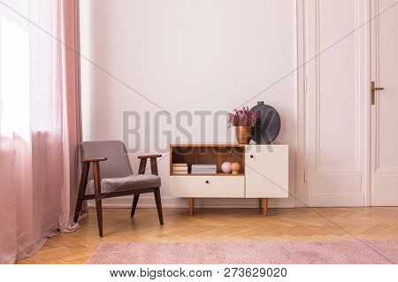 Grey Vintage Armchair Next To Wooden Cabinet With Books And Heather In Pot, Real Photo With Copy Spa