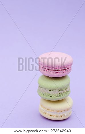 Three Macaroon Yellow, Green And Pink On A Purple Background.