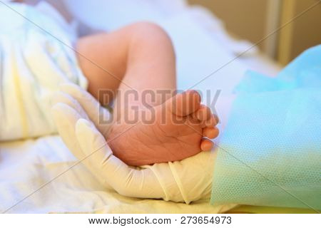 Doctor Holding Newborn Child's Foot In Hospital, Closeup