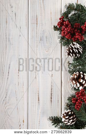 Spruce Branches, Cones And Red Berries On A White Wooden Background. Background For Christmas And Ne