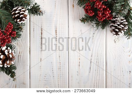 Spruce Branches, Cones And Red Berries On A White Wooden Background. Background For Christmas And Ne