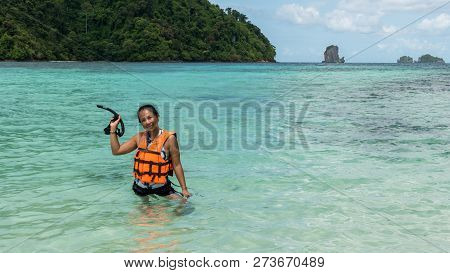 Woman Standing In Water In Orange Life Jacket Holding Mask And Snorkle
