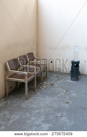 A Close Up Side View Of Three Brown And Cream Connected Seats Outside In A Designated Smoking Area W