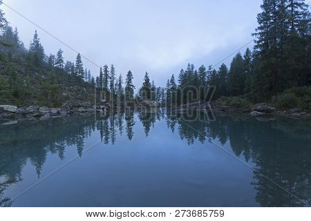 Reflection Of The Shore Of The Lake In The Watery Surface. A Misty Summer Morning. The Large (lower)