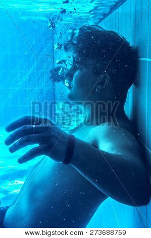 Young Attractive Caucasian Man Slowly Falls Down On The Pull Floor, Underwater. Blue And Deep Aquama