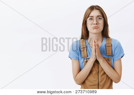 Waist-up Shot Of Silly Cute Charismatic Girl In Need Wearing Glasses And Brown Overalls Pursing Lips