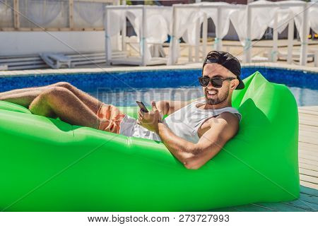 Young Man Enjoying Leisure, Lying On The Air Sofa Lamzac, Near The Pool