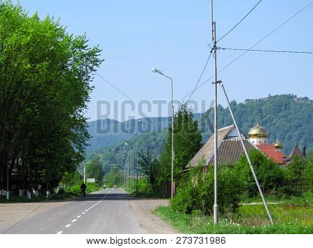 Summer Landscape Of Ivan Chendey Street In Khust With The Ruins Of An Ancient Fortress On A Hill. Be