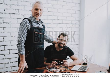 Two Men Repairing Hardware Equipment In Workshop. Repair Shop. Worker With Tools. Computer Hardware.