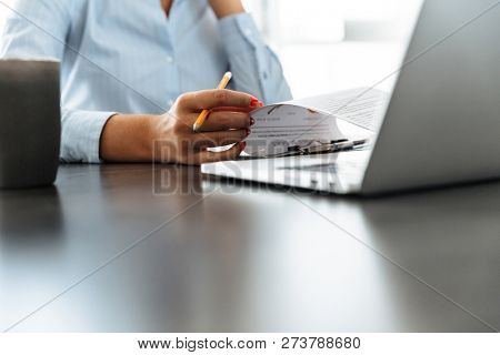 Close up of a woman working with laptop and documets at the table at home