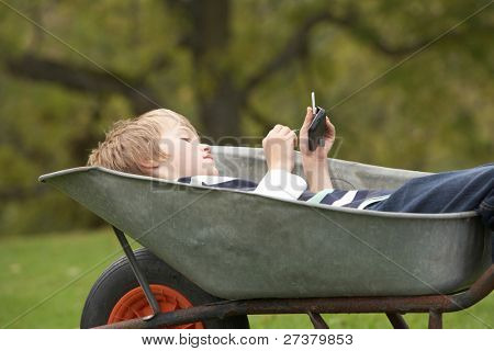 Jonge jongen leggen kruiwagen met behulp van slimme mobiele telefoon