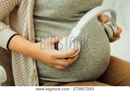 Pregnant Woman Holding Earphones Near Her Belly